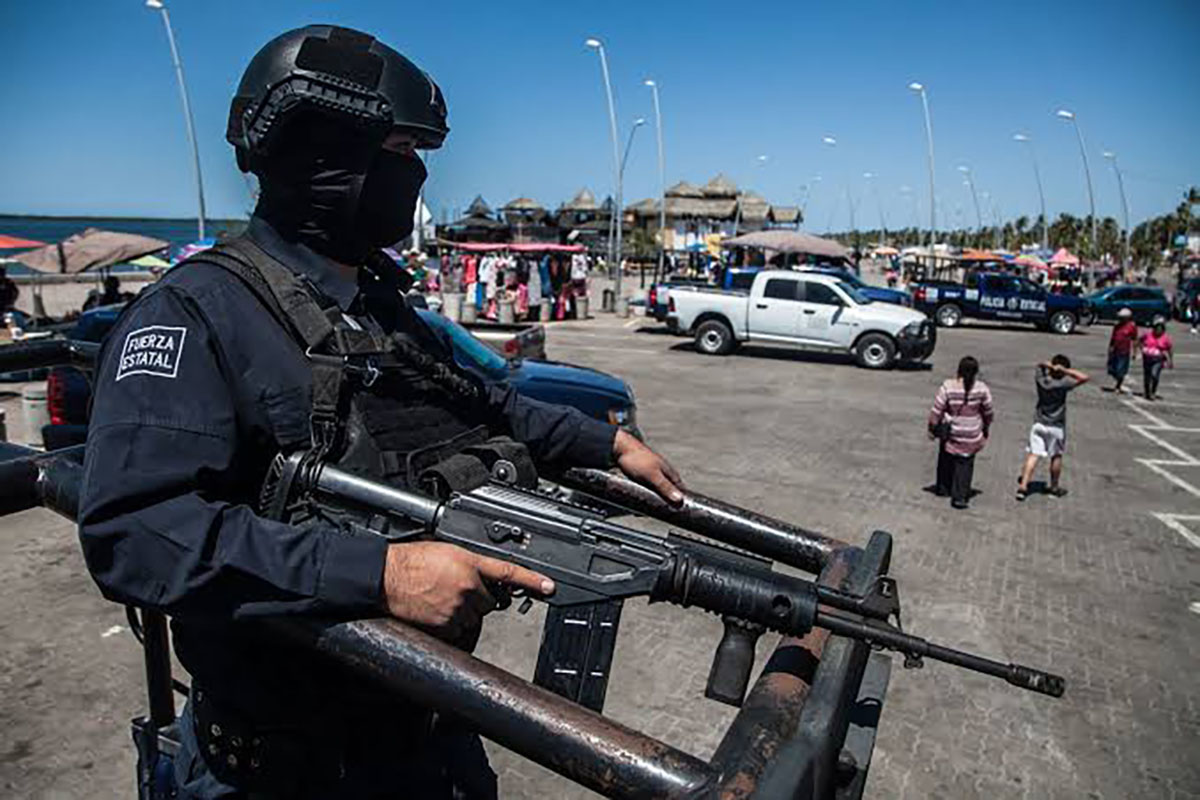Elemento de la Policía Estatal Preventiva montando guardia arriba de una patrulla de la corporación