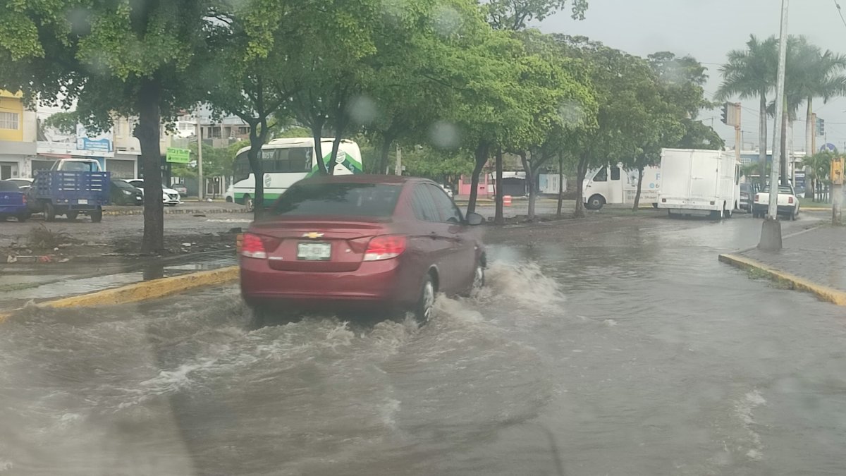 vehículo circulando por una calle con agua en lluvia