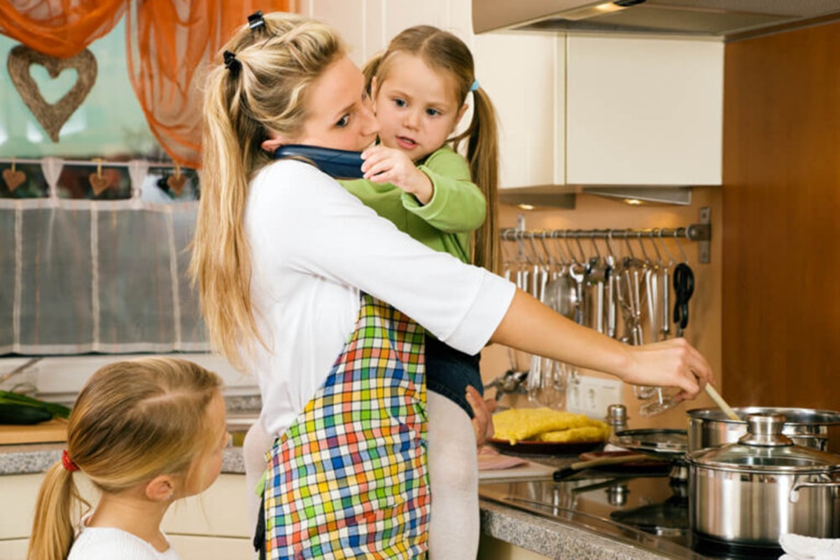 Mamá con sus hijas haciendo comida y hablando por teléfono