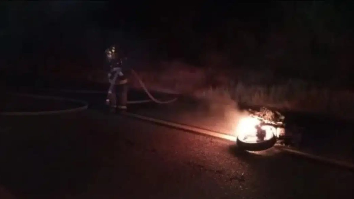 Bombero apaga fuego de motocicleta accidentada en la carretera